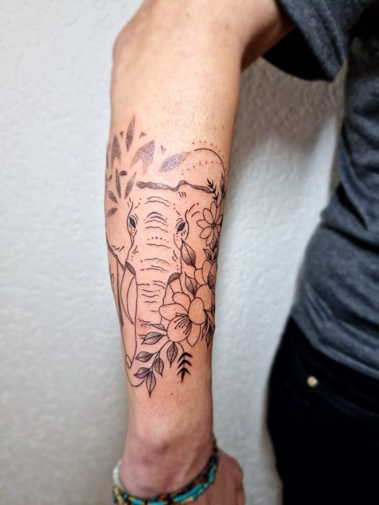 Avant-bras tatoué avec un dessin floral détaillé en noir, par By Meloun