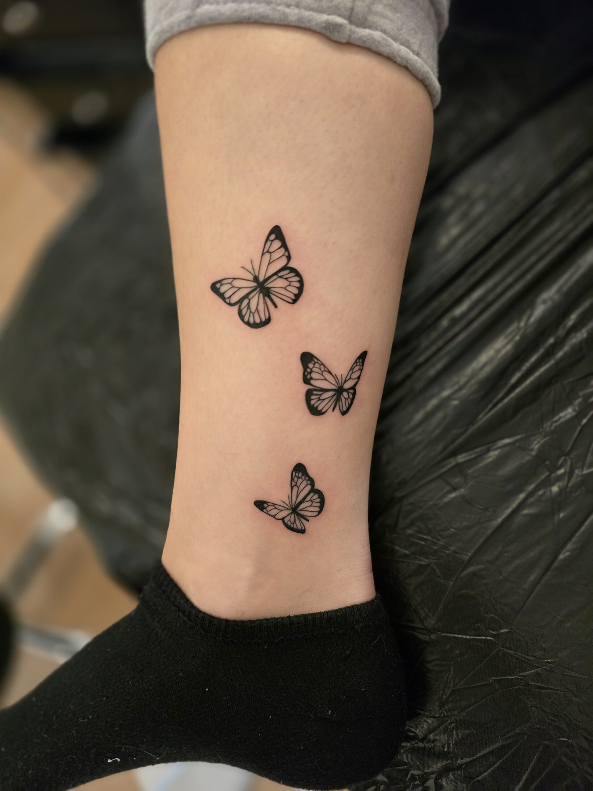 Tatouage de trois papillons sur la jambe, réalisé par By Meloun
