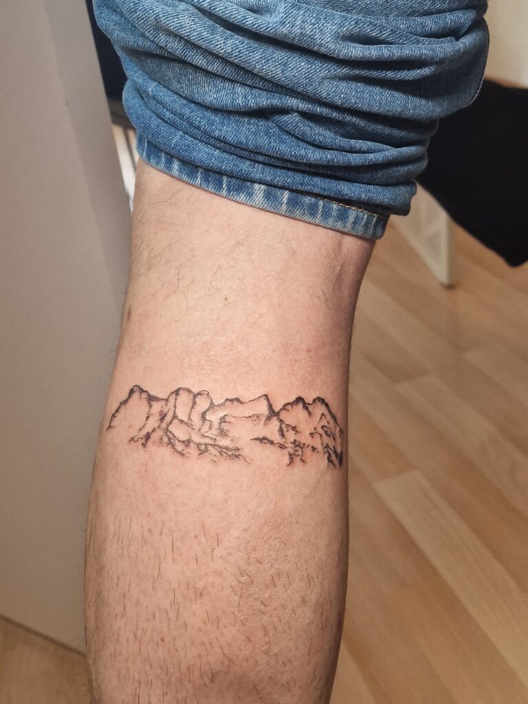 Tatouage de paysage montagneux sur la jambe, réalisé par By Meloun